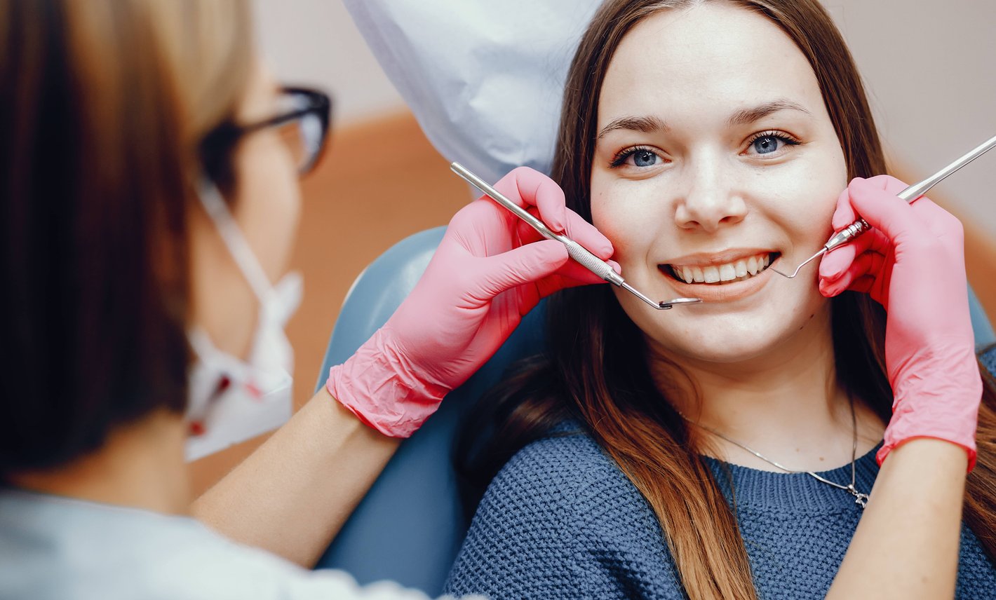 Dentist examining smiling female patient in dental chair